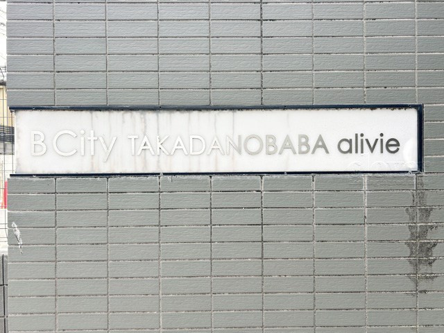 【現況写真】 | B CITY 高田馬場alivie | エントランスに掲げられた、マンション名を示す館銘板。さほど激しく主張はしませんが、しっかりと掲示されています。～即日のご見学可能～　お問合せはお気軽にどうぞ。