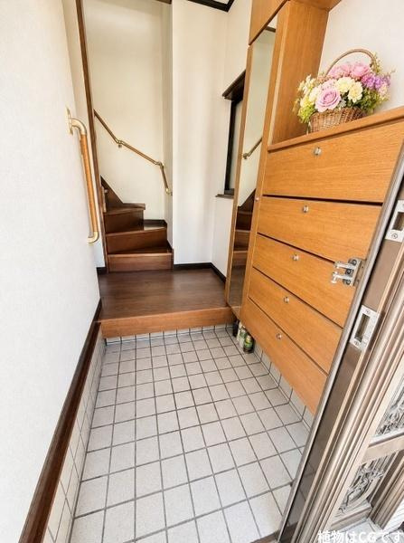 枚方市 東香里元町　中古 一戸建ての玄関|玄関を開けると、木の温もりを感じる落ち着いた空間がお出迎え。大容量のシューズ収納で玄関まわりをすっきり保てます。階段には手すりも備わり、毎日の出入りに便利な工夫が詰まった住まいです。