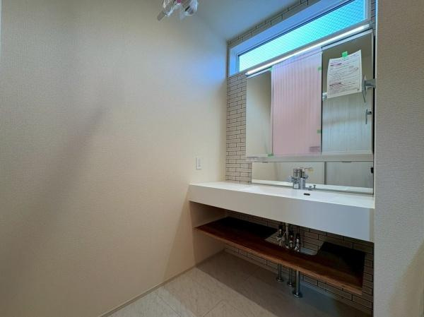 大和市上和田の新築一戸建の独立洗面台|鏡付きの洗面台と収納が設けられています。白を基調としたシンプルなデザインです。洗濯機置場もあり使い勝手が良い印象です。空間がすっきりとまとまっています。