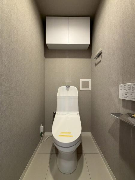 アリュール鶴見寺谷のトイレ|落ち着きのある空間にシンプルなデザインのトイレが設置されています。収納棚が設けられており日用品の整理にも便利です。壁リモコン式で操作も手軽に行えます。床はお手入れしやすい素材が使われています。