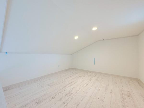 横浜市旭区川井本町の中古一戸建の内装|シンプルなデザインのロフト空間です。天井が斜めになっており個性的なスペースが広がります。明るい色合いのフローリングが全体をより広く感じさせます。照明も設置されており夜間でも充分な明るさを確保できます。