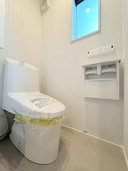 横浜市旭区川井本町の中古一戸建のトイレ|トイレは明るいカラーでまとめられており清潔感が感じられます。窓が設置されており換気にも配慮されています。壁に操作パネルとペーパーホルダーがあり機能的な空間となっています。