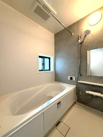 静岡市葵区田町７期　新築戸建　全７棟　F号棟の浴室|グレーのアクセントパネルが落ち着いた印象の浴室。窓と浴室乾燥機を備え、明るく使い勝手のよい空間です。