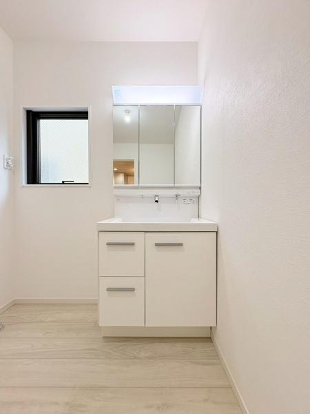 大和市上和田の新築一戸建の独立洗面台|鏡付きの洗面台と収納が設けられています。白を基調としたシンプルなデザインです。