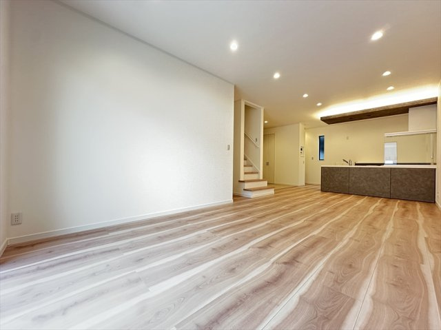 【居間・リビング】 | 志木市柏町2丁目　新築一戸建住宅　全2棟　(志木本店) | リビング階段を採用し、家族が自然と顔を合わせやすい間取り。キッチン上部の折り下げ天井と間接照明が空間にアクセントを添え、木目調のフローリングと調和した印象的なリビングです。