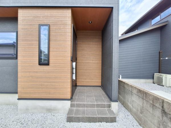フォレクス片島5　B棟の玄関|落ち着いた色合いのタイルと木目調の壁が調和した玄関です。シンプルながらも洗練されたデザインが印象的です。屋根付きなので天候の影響も受けにくく安心です。玄関アプローチがすっきりとしています。
