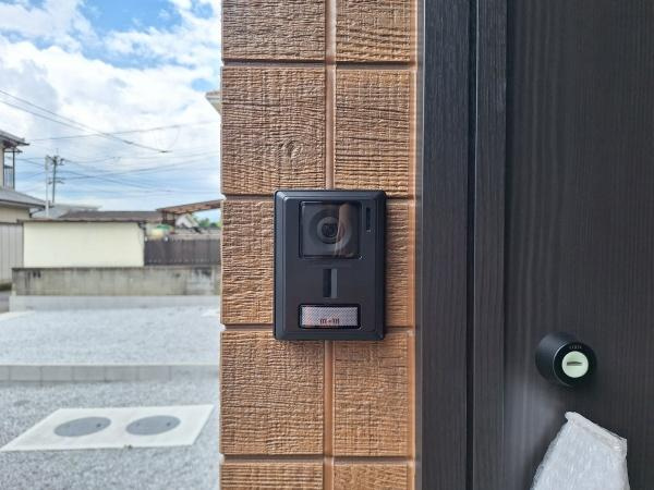 フォレクス片島5　B棟の玄関|玄関にはカメラ付きインターホンが設置されており訪問者の確認が可能です。外観の壁材は落ち着いた色合いで門周りもすっきりと整っています。インターホンの下にはネームプレートが付いています。