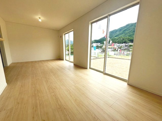 【居間・リビング】 | 安佐北区亀山8丁目（全2区画）No2 | 2面の大きな掃き出し窓から豊かな自然光が差し込むリビング。窓の外には広々としたお庭スペースが広がり、室内からも周囲の山々を望む開放的な景色が楽しめます。明るくのびのびと過ごせる空間設計です。
