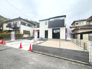 【外観】 | 佐伯区美鈴が丘西4丁目（全1棟） | 白を基調とした外壁に、シックな黒のアクセントを効かせたモダンな外観デザイン。南向きに配置された大きな窓とバルコニーが特徴で、建物前面にはカースペースとお庭が広がっています。