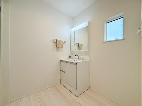 横浜市旭区金が谷２丁目の新築一戸建の独立洗面台|ナチュラルな色合いで統一された洗面台が清潔感を醸し出しています。収納スペースがしっかり確保されシンプルなデザインが魅力的です。窓から自然光が入り明るい雰囲気になっています。