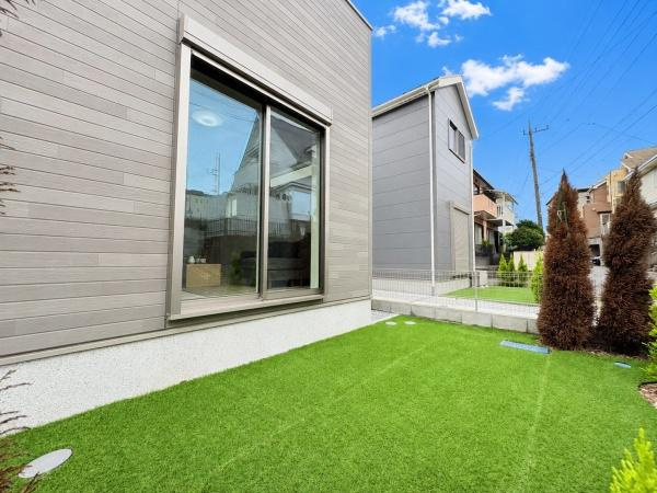 横浜市旭区金が谷２丁目の新築一戸建の庭|手入れがしやすい人工芝が敷かれた庭です。窓が大きく開放感を感じます。日当たりもしっかり確保されています。周囲の住宅とも程よい距離感です。シンプルな外観で色々な使い方が考えられます。