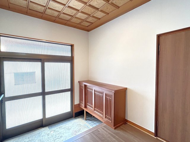 桜川市青柳　中古戸建の玄関|【リフォーム完成・即入居可】玄関の写真です。フローリング重ね張、クロス張替、照明交換等行いました。引き戸のスリットから自然光が差し込み、明るい印象の空間になっています。