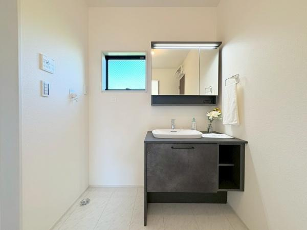 大和市福田の新築一戸建の独立洗面台|鏡付きの洗面台と収納が設けられています。グレーを基調としたシンプルなデザインです。洗濯機置き場もあり使い勝手が良い印象です。