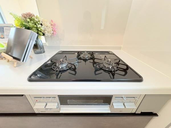大和市福田の新築一戸建のキッチン|清潔感のあるホワイトカラーのキッチンは収納スペースもしっかり確保されています。広い作業台で調理がはかどります。ガスコンロと換気扇が設置されており使いやすさに配慮されたレイアウトです。
