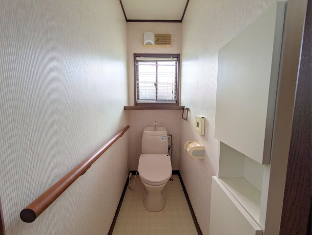 白水台1丁目戸建のトイレ|温かみのある内装のトイレです。小窓から自然光が入り、収納棚や手すりなど充実の設備が整います。