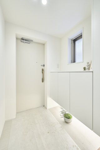 クレッセント東中野レジデンスの玄関|白を基調とした明るい玄関に、小窓からの自然光がやさしく差し込み、空間に心地よい明るさを添えています。足元が浮いたシューズボックスが軽やかな印象を生み、玄関全体をスッキリとみせてくれます