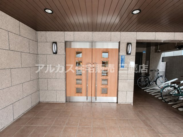 ベルジュール三鷹のエントランス|木目調の両開き扉と石調の壁面が調和した、落ち着きのある共用エントランスです。