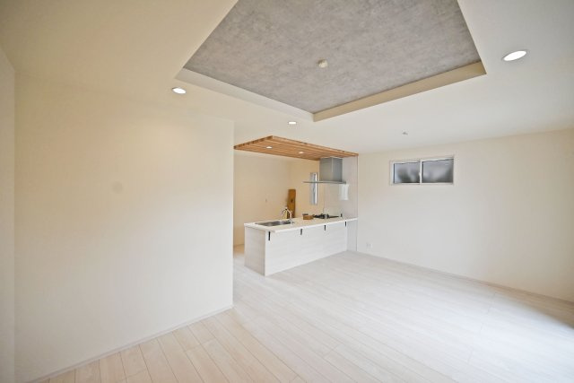 ブルーミングガーデン山本野里2丁目新築戸建て│3LDK+駐車2台可の居間・リビング|グレーの折上天井が空間に奥行きを生み、木目の折下げ天井がキッチンを美しく引き立てます。白を基調とした室内は家具の色も合わせやすく、ダイニングとリビングを思い思いにコーディネートできるのも楽しみですね。