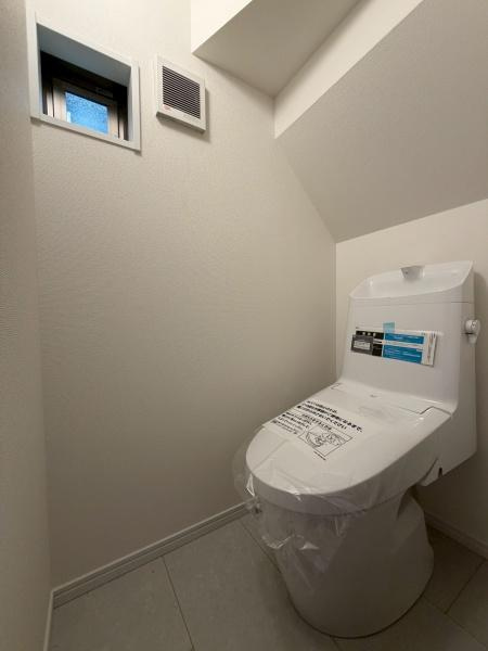川崎市川崎区小田２丁目の新築一戸建のトイレ|トイレ空間が明るく清潔感があります。換気用の窓と通気口があり快適性が感じられます。ゆとりのある設計で使いやすさにも配慮されています。シンプルで落ち着いた雰囲気が魅力のトイレです。