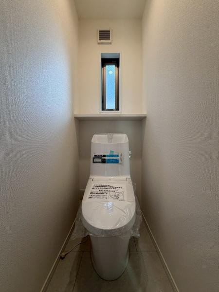川崎市川崎区小田２丁目の新築一戸建のトイレ|コンパクトな空間に設置されたトイレです。小窓が付いており換気も可能です。明るい内装が清潔感を演出しています。床や壁がシンプルなデザインとなっています。すっきりとした印象のトイレスペースです。