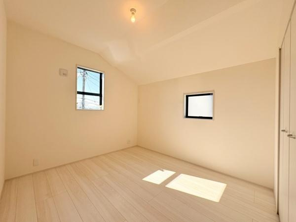 横浜市緑区いぶき野の新築一戸建の洋室|明るい光が差し込む洋室です。二面採光により室内が開放的な印象となっています。壁と床のカラーが落ち着いた印象を与えます。天井の形状が特徴的で空間のアクセントとなっています。収納スペースも備わっています。