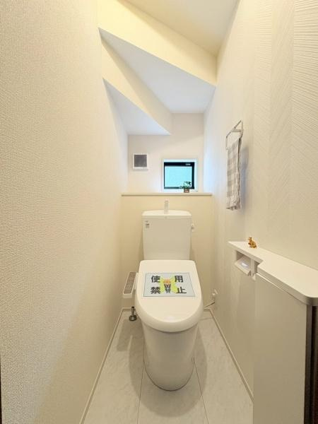 横浜市緑区いぶき野の新築一戸建のトイレ|明るい光が差し込むトイレ空間です。壁面もすっきりとしており清潔感があります。窓付きで換気もしやすい設計です。コンパクトながら必要な設備がまとめられていて使いやすいです。収納スペースも備わっています。