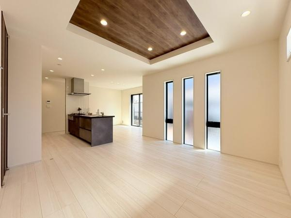 横浜市緑区いぶき野の新築一戸建の居間・リビング|天井に施されたアクセントパネルが空間を引き締め洗練された印象を与えます。3つ並んだ縦長窓から自然光が豊かに差し込みリビング全体が明るく感じられます。