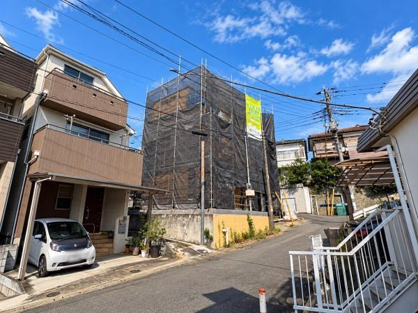 横浜市保土ケ谷区仏向西の新築一戸建の前面道路含む現地写真|角度を変えて撮影した現地外観。前面道路から建物全体の位置関係を確認しやすく、周辺の住宅街の様子も伝わります。工事の進捗とあわせて、実際の街並みや現地までのアプローチも現地でぜひご確認ください。