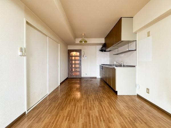 エメラルドマンション古国府のキッチン|キッチンとリビングが一体となった開放感のある空間です。木目調のフローリングが温かみを演出しています。壁付けキッチンでお部屋がすっきりと使えます。収納スペースも豊富に確保されています。