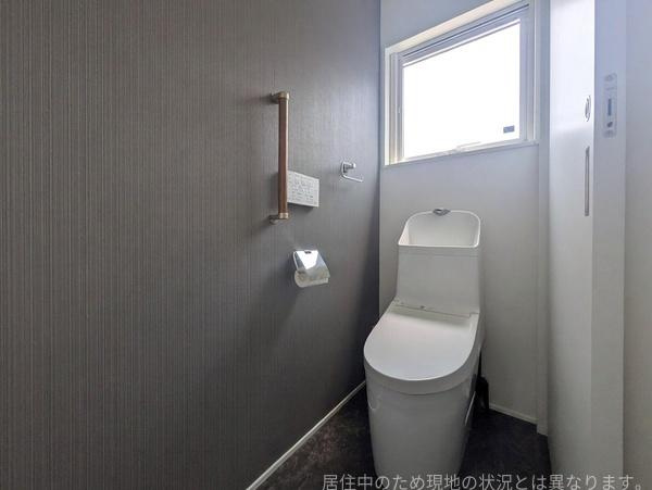 浜中中古のトイレ|窓付きで採光と換気に優れたトイレです。落ち着いた色合いのアクセントクロスが上質な空間を演出し、手すりを備えるなど使いやすさにも配慮されています。
