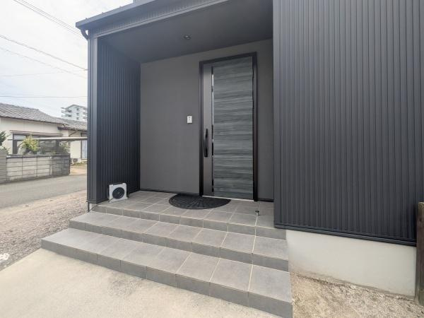 浜中中古の玄関|落ち着いた色合いと洗練されたデザインが印象的な玄関です。段差を抑えた設計で出入りもスムーズ。屋根付きのアプローチが、雨の日でも快適な動線を確保します。