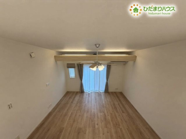 熊谷市野原　中古一戸建ての展望|※AIにて残置物加工
小屋裏収納から見下ろす、開放感あふれるリビングの眺めです！おしゃれなシーリングファンや柔らかな光が差し込む窓辺が一体となり、ご家族の温かい気配を感じながら心地よく過ごせます♪