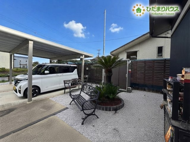 熊谷市野原　中古一戸建ての庭|カーポートやおしゃれなベンチが配置された、ゆったりとくつろげる開放的な駐車スペースです！手入れのしやすい砂利敷きとおしゃれな植栽が施され、毎日心地よく過ごせます♪