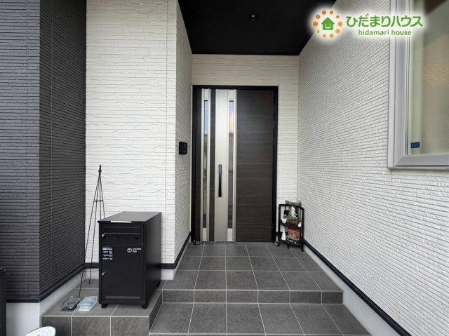 熊谷市野原　中古一戸建ての玄関|※AIにて残置物加工
モノトーンの外壁が洗練された雰囲気を醸し出す、モダンな印象の玄関ポーチです！便利な宅配ボックスも設置され、機能面も充実した心地よい空間です♪