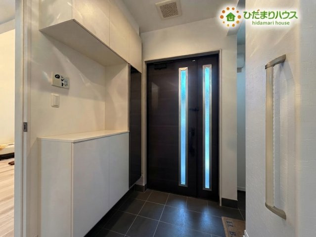 熊谷市野原　中古一戸建ての収納|※AIにて残置物加工
大容量のシューズボックスが備えられた、すっきりと片付く使い勝手の良い玄関です！白を基調とした明るい空間にダークカラーのドアが映え、毎日の出入りを気持ちよくサポートしてくれます♪