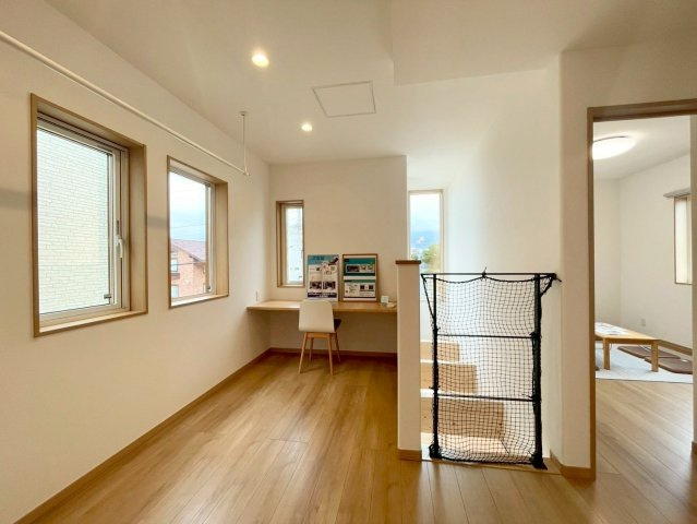西野４条７丁目　新築戸建の居間・リビング|吹抜けからやさしい陽光が差し込む2階フリースペース。カウンター付きで、テレワークやお子様の学習にもおすすめ。室内物干しを備え、来客時の室内干しにも便利◎