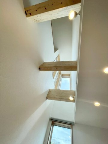 西野４条７丁目　新築戸建の内装|リビング吹抜け写真。大きな窓からやさしい陽光が差し込み、木の梁が住まいに上質な温もりを添えます