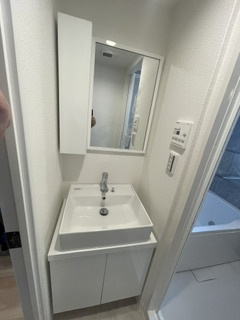 田園調布コーポラスの独立洗面台|白を基調とした清潔感あふれるスタイリッシュな独立洗面台。身支度に便利な大きな三面鏡や小物を整頓できる収納スペース、使いやすい洗面ボウルを備えており、毎日の身支度を快適に行えます。