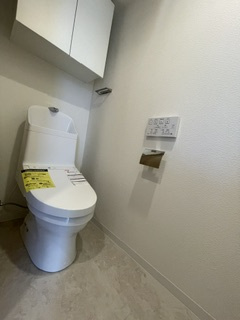 田園調布コーポラスのトイレ|清潔感のある温水洗浄便座付きのトイレ空間。上部にはトイレットペーパーや掃除用品などをすっきりと目隠しして収納できる、便利な吊戸棚（収納スペース）を備えています。