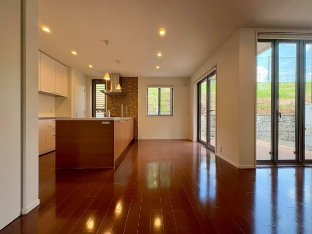 草津市岡本町　中古戸建ての居間・リビング|キッチンからリビングとデッキを見渡せる設計。家事中も家族の気配を感じられます。