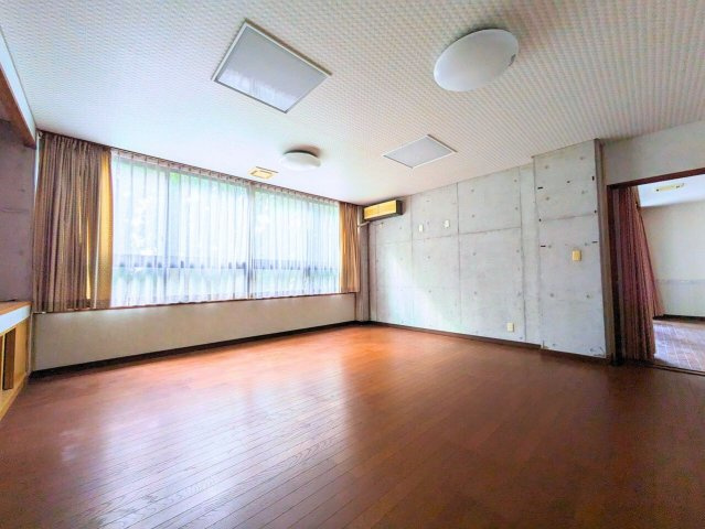 吉藤5丁目3世帯戸建ての洋室|窓からの眺望と、スタイリッシュなコンクリート打ち放しの壁が、お部屋にモダンなアクセントを加えます。