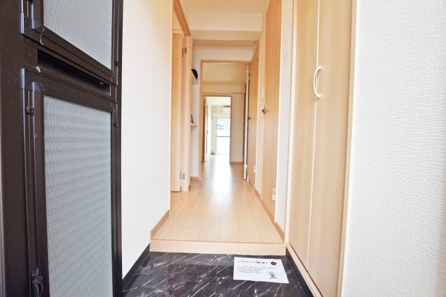 日商岩井中津マンションの玄関|玄関外から撮影した写真です。床や壁の明るさを際立たせるように土間スペースには落ち着いた色が配置されています。