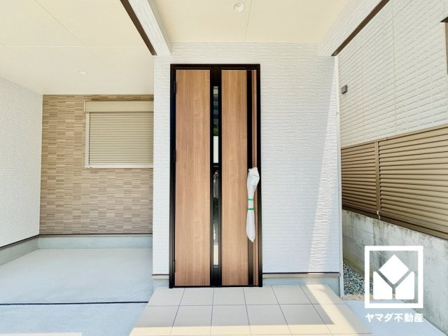 西宮市笠屋町の玄関|オーバーハング部分を活用した一部屋根付きの駐車スペースになっており、雨の日も車と玄関を行き来しやすい設計です。