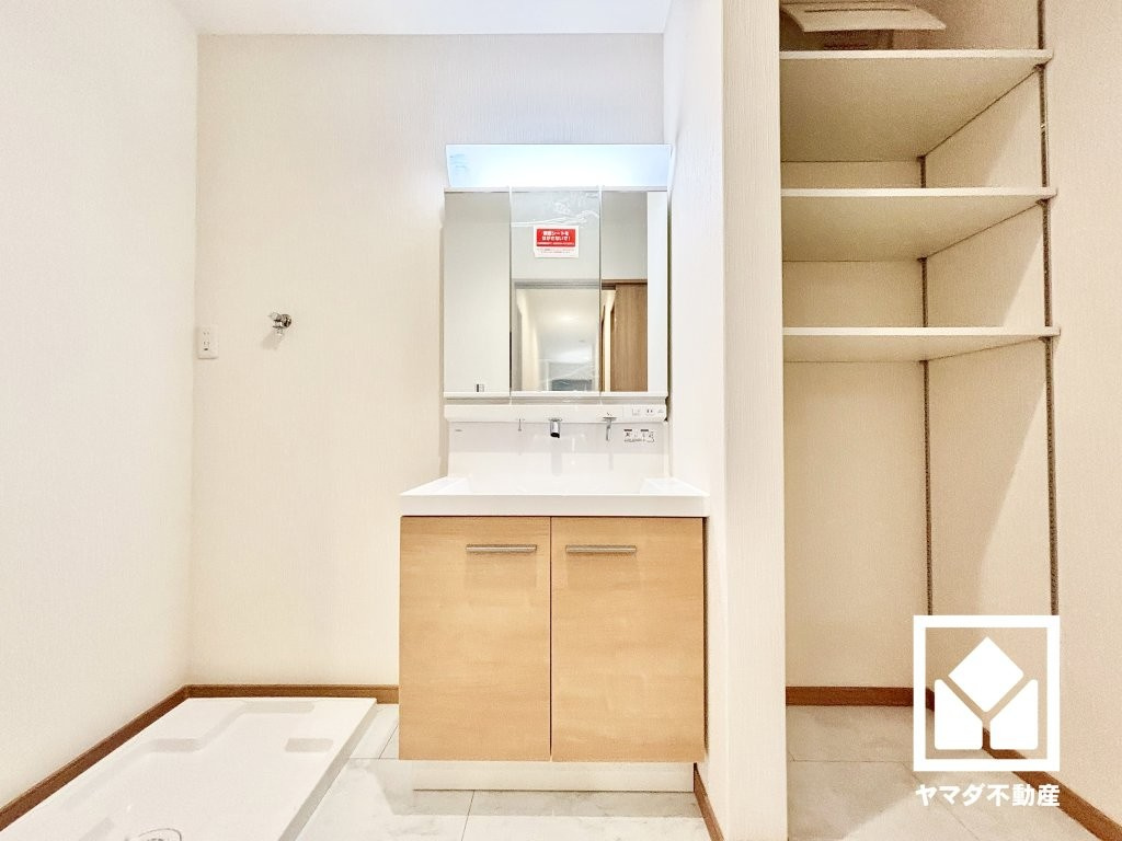 西宮市笠屋町の洗面所|洗面化粧台はLIXIL EVを採用。一体形カウンターやフランジのない排水口など、お手入れに配慮された仕様です。隣には稼働棚のリネン庫も備えており、洗面室をすっきり清潔に保つことができそうです。