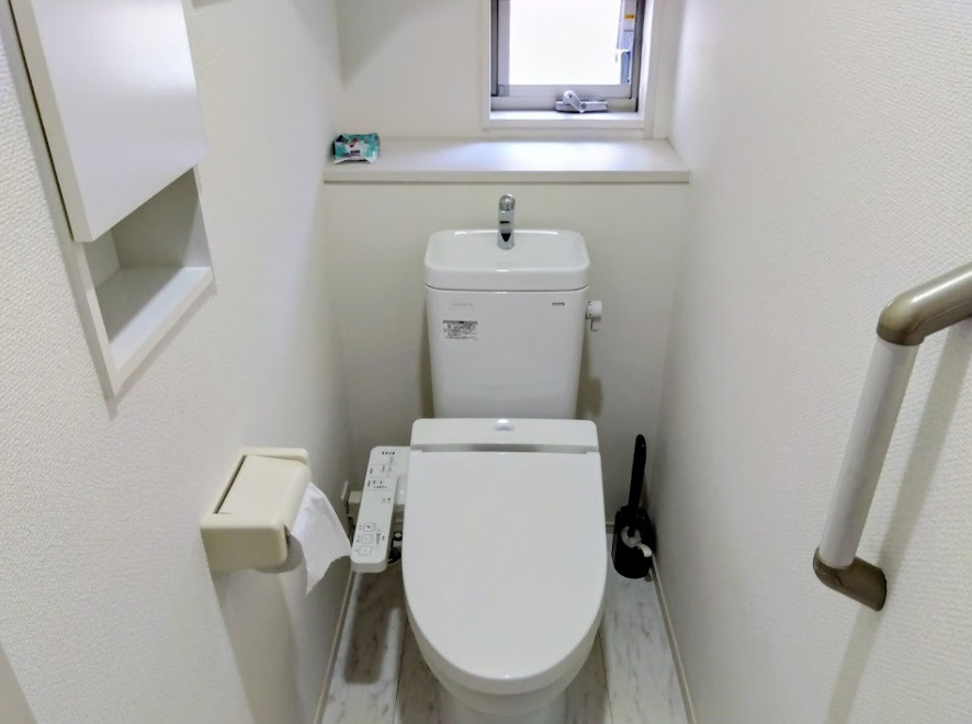 売中古戸建　三島市安久のトイレ|清潔感あふれる白を基調としたトイレです。温水洗浄便座や手すり、小窓付きで快適性と安心感を兼ね備えています。