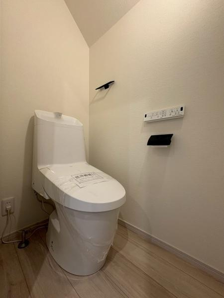 横浜市鶴見区梶山１丁目の新築一戸建のトイレ|シンプルで清潔感のあるトイレ空間です。壁面にリモコンやペーパーホルダーが設置され使い勝手に配慮されています。フローリングの色合いが落ち着いた雰囲気を演出しています。