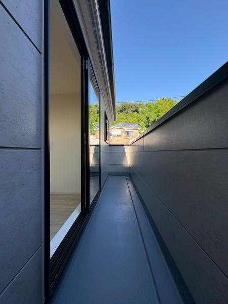横浜市鶴見区梶山１丁目の新築一戸建のバルコニー|バルコニーはゆとりのある設計で明るい日差しをしっかり取り込めます。外壁の落ち着いた色合いと調和した空間となっています。窓からのアクセスもスムーズで室内との一体感が感じられます。