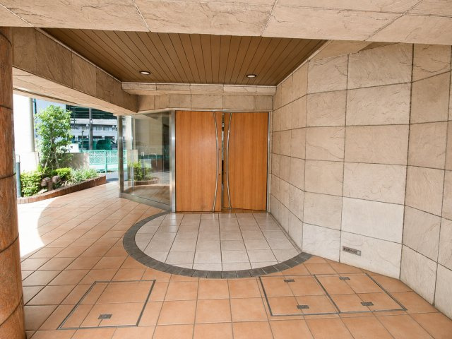 マイキャッスル高井戸のエントランス|重厚感のある石調タイルと木目ドアが調和した、風格漂うマンションアプローチ。