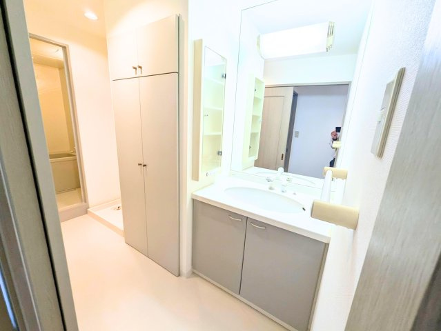 サンクレスタ緑町の洗面所|身支度に便利な大きな鏡付きの洗面化粧台。足元や鏡の横に小物をしまえる収納スペースを完備。