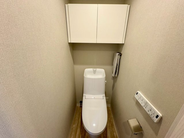 「商業施設充実」サーパス鏡川大橋　中古マンションのトイレ|白を基調とした清潔感あふれるトイレ空間。上部には便利な吊戸棚があり、掃除用品などの収納に便利です。